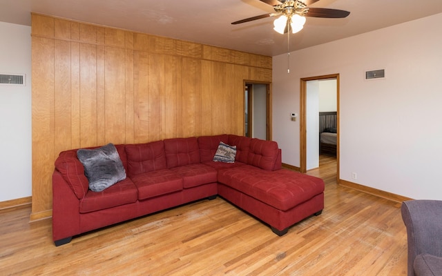 living room featuring wood walls, ceiling fan, and light hardwood / wood-style floors