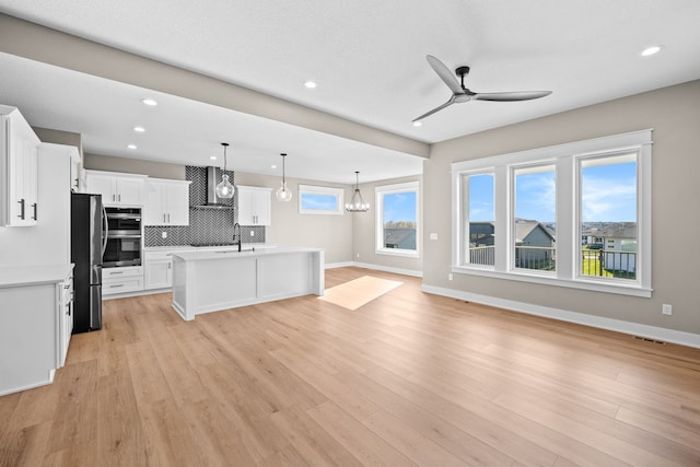 kitchen featuring light hardwood / wood-style floors, white cabinets, an island with sink, and appliances with stainless steel finishes