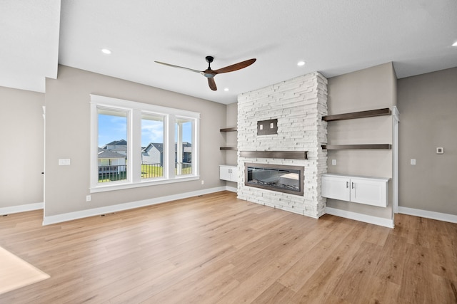 unfurnished living room featuring a textured ceiling, ceiling fan, light wood-type flooring, and a fireplace