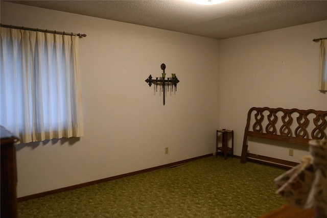 unfurnished bedroom with dark carpet and a textured ceiling