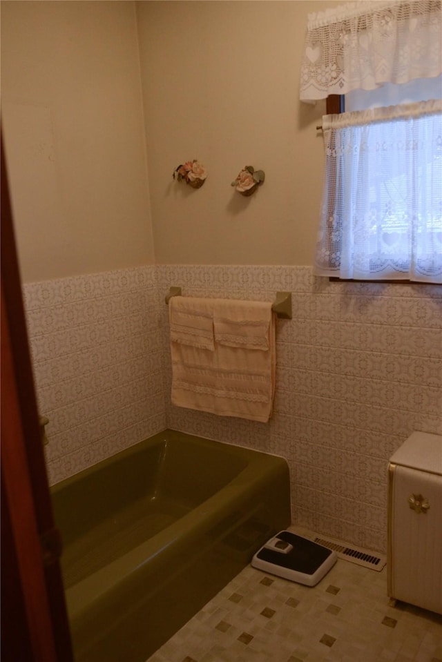 bathroom with a tub to relax in and tile walls