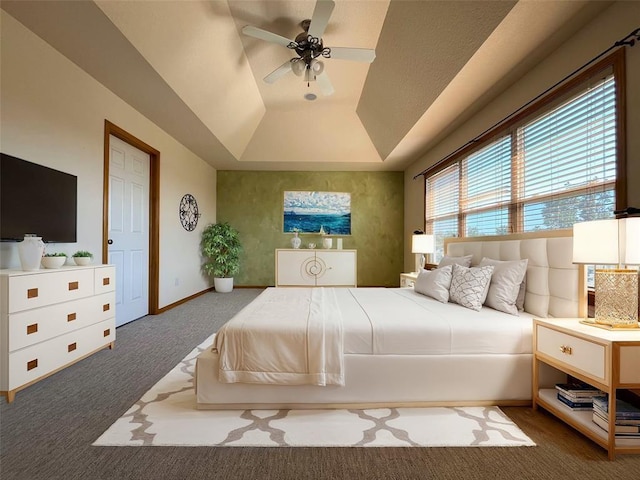 bedroom featuring a tray ceiling, ceiling fan, and dark colored carpet