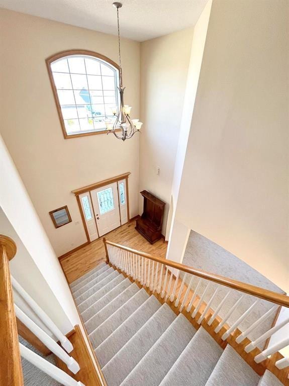 staircase featuring hardwood / wood-style floors and an inviting chandelier