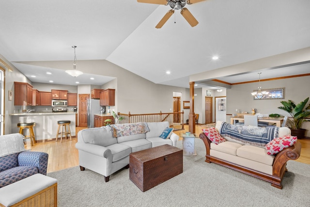 living room featuring ornate columns, ceiling fan with notable chandelier, vaulted ceiling, and light wood-type flooring