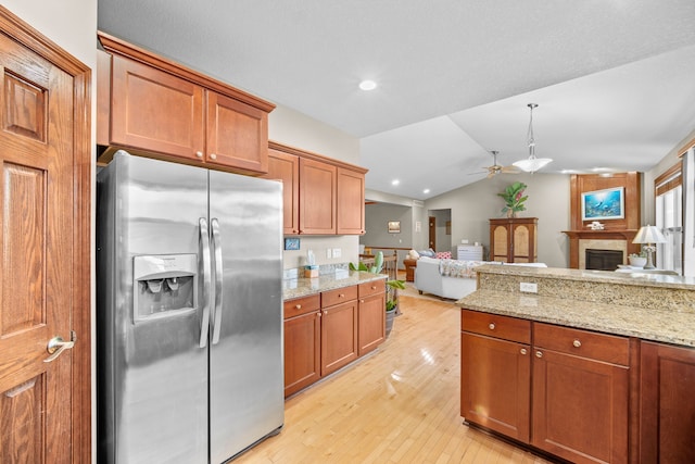 kitchen featuring lofted ceiling, hanging light fixtures, ceiling fan, stainless steel fridge, and light hardwood / wood-style floors