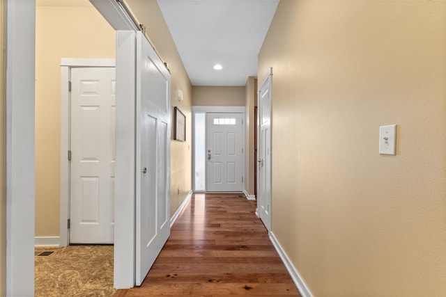 hall featuring a barn door and hardwood / wood-style flooring