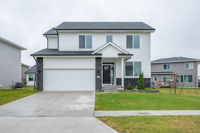 view of front of home with cooling unit, a garage, and a front yard