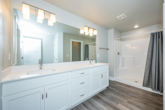 bathroom featuring hardwood / wood-style flooring, vanity, and walk in shower