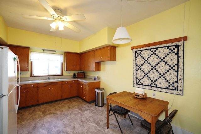 kitchen with ceiling fan, white refrigerator, sink, and hanging light fixtures