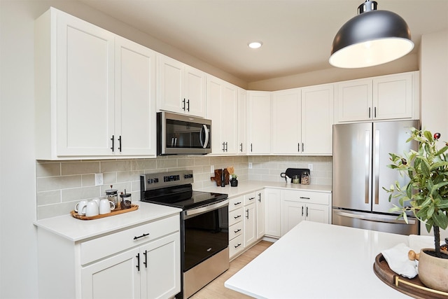 kitchen featuring hanging light fixtures, appliances with stainless steel finishes, tasteful backsplash, light hardwood / wood-style floors, and white cabinetry