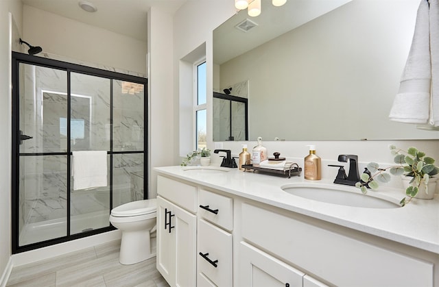 bathroom featuring vanity, toilet, and a shower with shower door