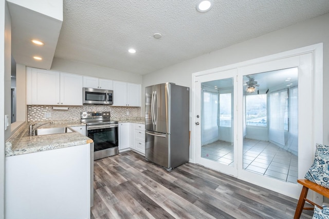 kitchen with dark hardwood / wood-style flooring, a textured ceiling, stainless steel appliances, sink, and white cabinets