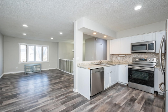 kitchen with white cabinets, sink, a textured ceiling, dark hardwood / wood-style flooring, and stainless steel appliances