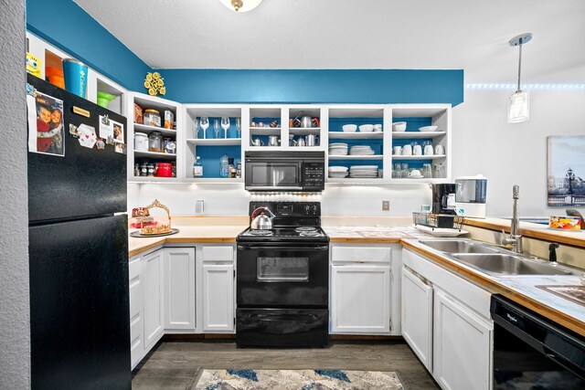 kitchen featuring dark wood-type flooring, sink, black appliances, white cabinets, and hanging light fixtures