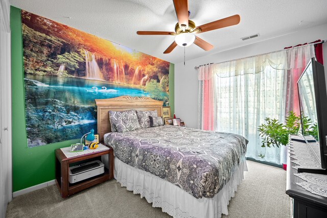 bedroom featuring a textured ceiling, ceiling fan, and light carpet