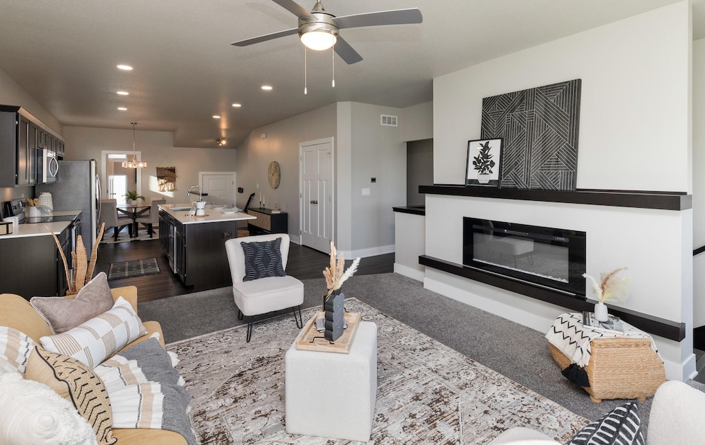 living room with ceiling fan with notable chandelier and dark wood-type flooring