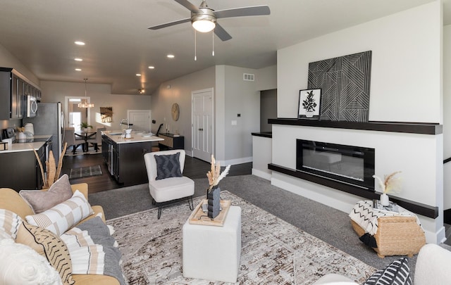 living room with ceiling fan with notable chandelier and dark wood-type flooring