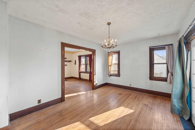 spare room with hardwood / wood-style floors, a textured ceiling, and a chandelier