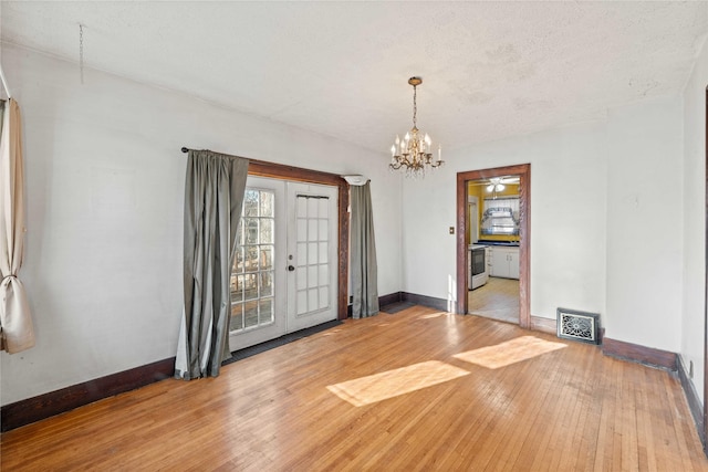 foyer entrance featuring french doors, wood-type flooring, a textured ceiling, and an inviting chandelier