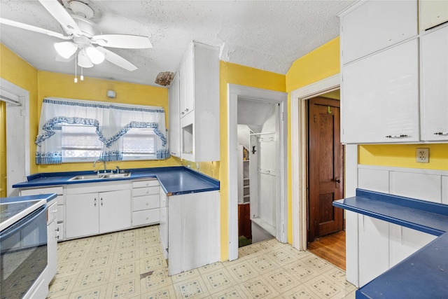 kitchen with white cabinetry, sink, ceiling fan, a textured ceiling, and electric stove