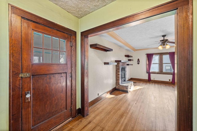 foyer featuring ceiling fan, a fireplace, a textured ceiling, and light hardwood / wood-style flooring