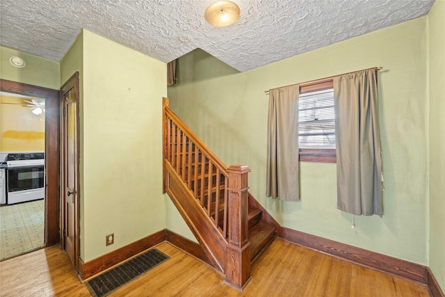 stairs with wood-type flooring and a textured ceiling