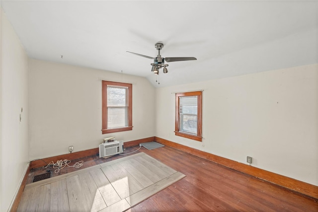 spare room with hardwood / wood-style flooring, an AC wall unit, and ceiling fan