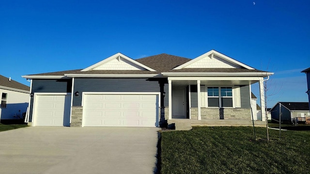 view of front of property featuring a porch, an attached garage, driveway, stone siding, and a front lawn