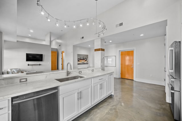 kitchen with white cabinets, hanging light fixtures, sink, appliances with stainless steel finishes, and light stone counters