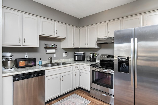 kitchen with sink, white cabinets, wood-type flooring, and appliances with stainless steel finishes