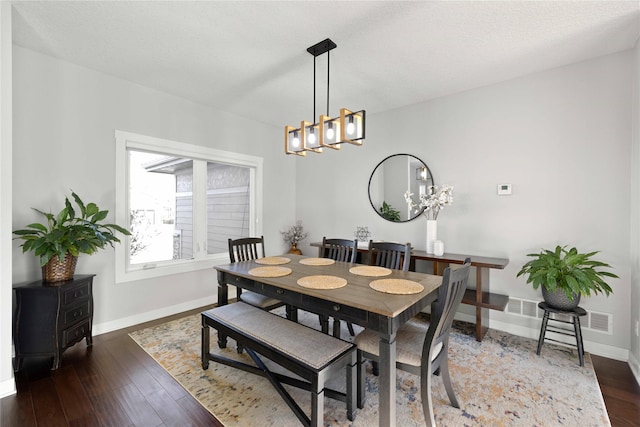 dining area featuring a textured ceiling, dark hardwood / wood-style flooring, and a notable chandelier