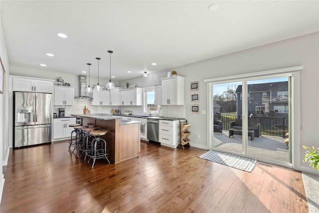 kitchen featuring pendant lighting, a center island, stainless steel appliances, and plenty of natural light