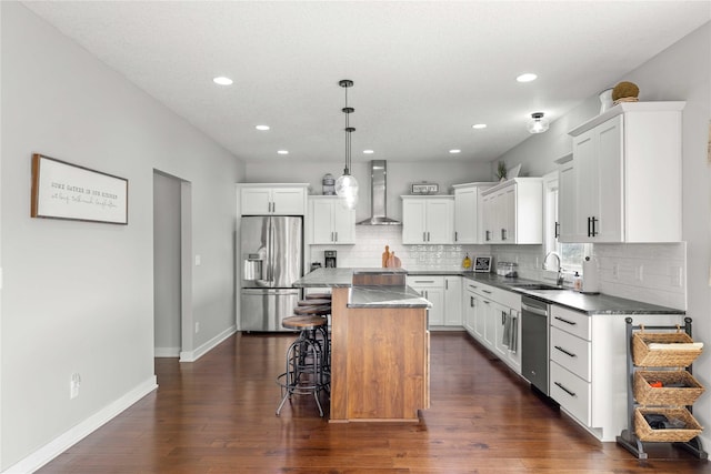 kitchen featuring dark wood-type flooring, a kitchen breakfast bar, wall chimney exhaust hood, appliances with stainless steel finishes, and a kitchen island