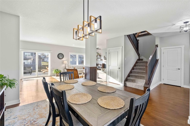 dining area with dark hardwood / wood-style flooring, a textured ceiling, and a notable chandelier