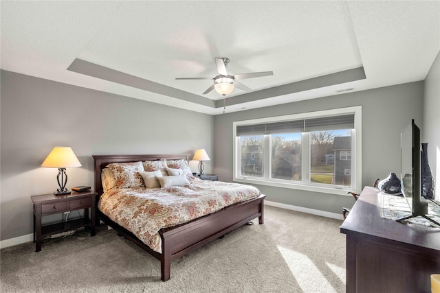 bedroom featuring carpet, a tray ceiling, and ceiling fan