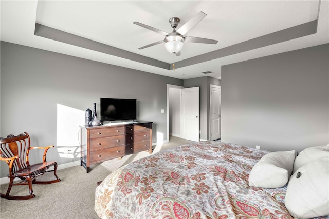 carpeted bedroom featuring a tray ceiling and ceiling fan