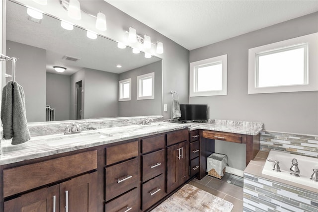 bathroom featuring tile patterned floors, a tub, vanity, and a textured ceiling