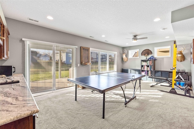 game room featuring a textured ceiling, ceiling fan, and light carpet