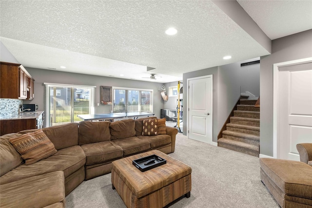 carpeted living room featuring a textured ceiling and ceiling fan