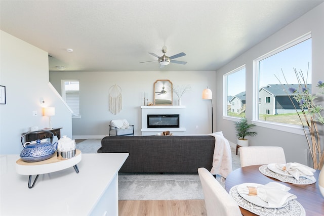 living room with ceiling fan, light hardwood / wood-style floors, and a textured ceiling