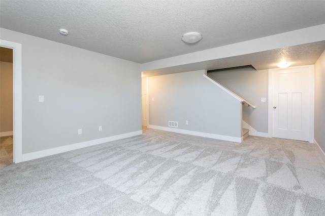 basement featuring light carpet and a textured ceiling