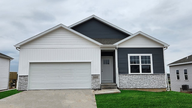 view of front of home with a garage, central air condition unit, and a front yard