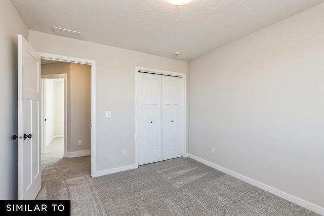 unfurnished bedroom with a textured ceiling, light carpet, and a closet