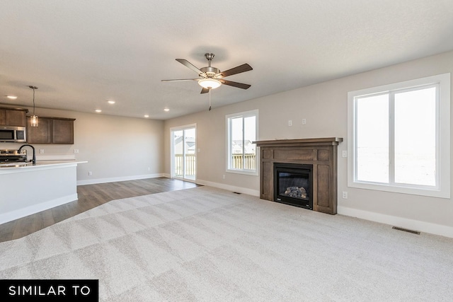 unfurnished living room featuring ceiling fan and light hardwood / wood-style floors