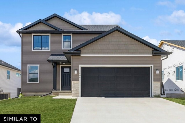 craftsman-style home with cooling unit, a front yard, and a garage