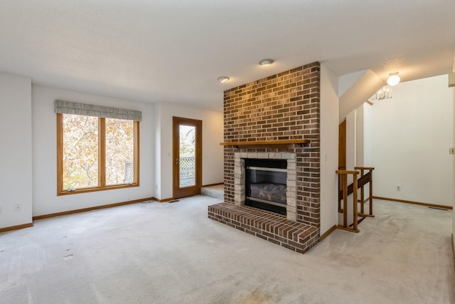 living room featuring carpet flooring, a fireplace, a textured ceiling, and a notable chandelier