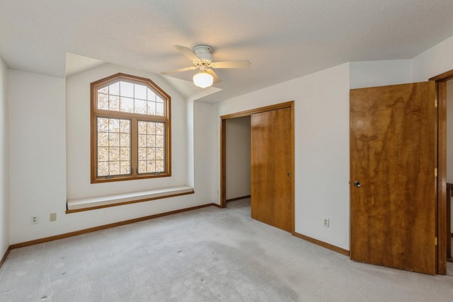 spare room featuring light colored carpet, a textured ceiling, and vaulted ceiling