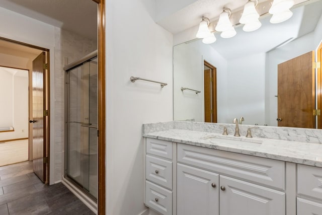 bathroom featuring wood-type flooring, vanity, and a shower with shower door