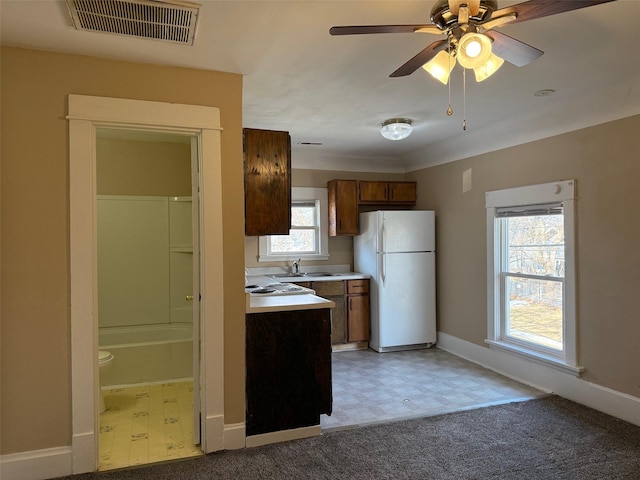 kitchen featuring white refrigerator, ceiling fan, sink, and carpet