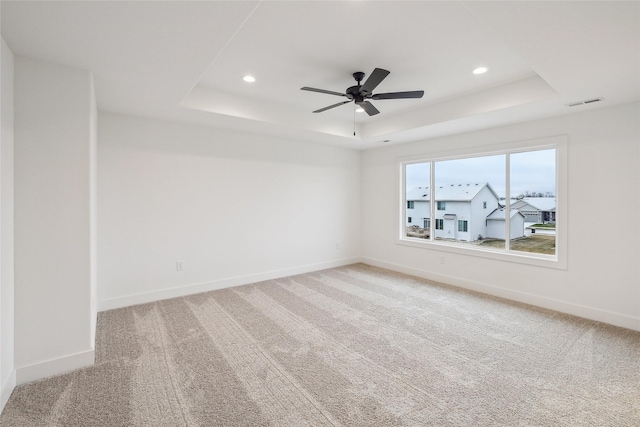 carpeted empty room featuring a raised ceiling and ceiling fan